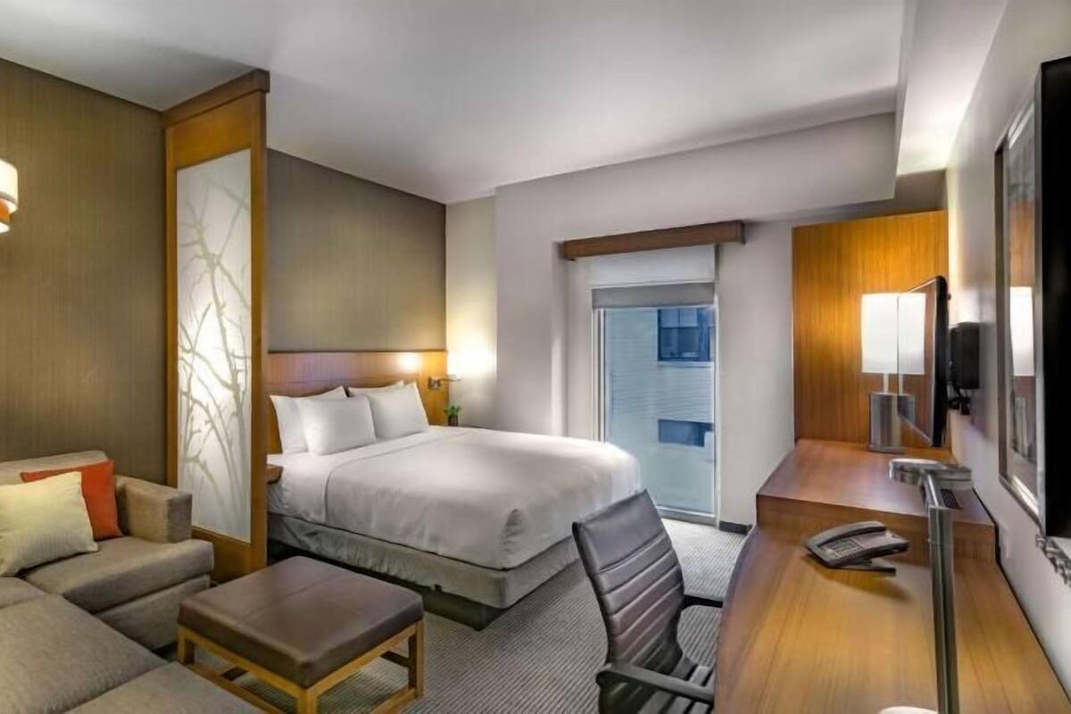 Una habitación de hotel con cama, sofá, escritorio y silla.