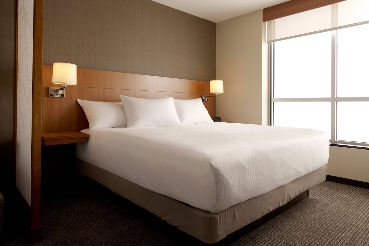A neatly made bed with white linens in a hotel room.