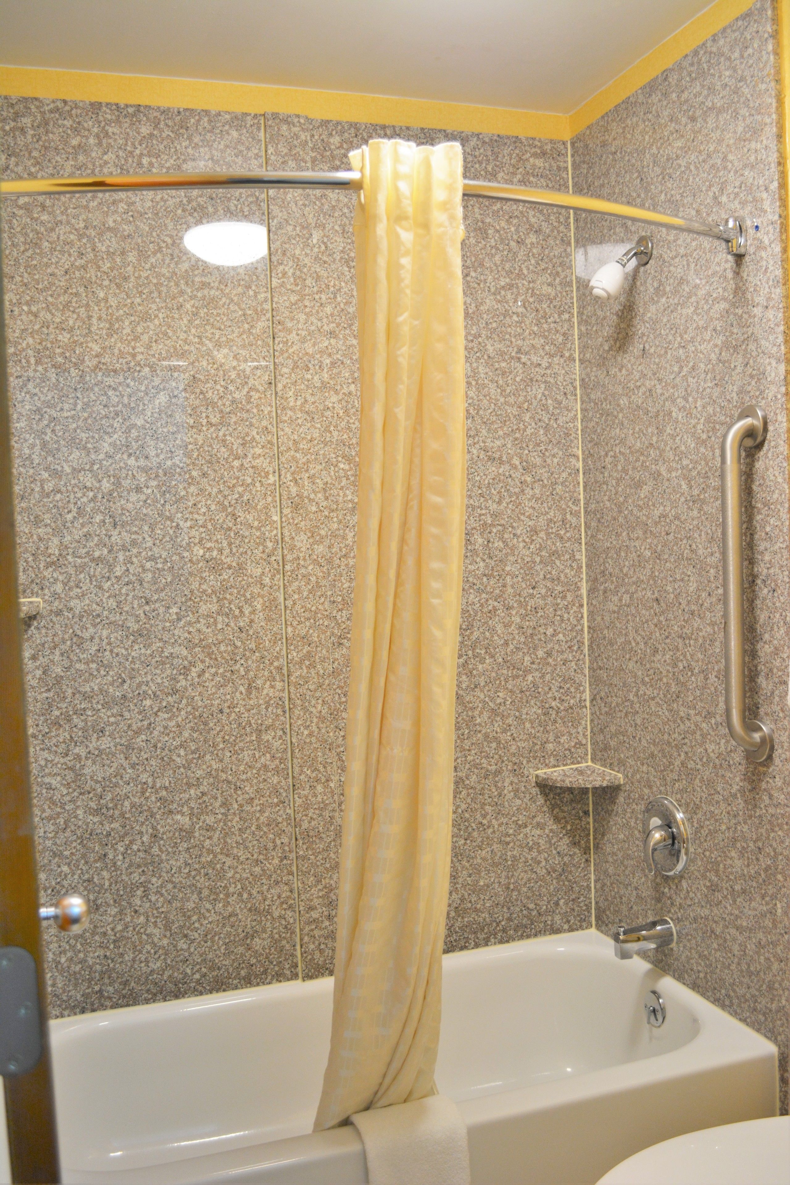 Ein Badezimmer mit einer Badewanne, einer Duschvorhang und einer Haltestange.