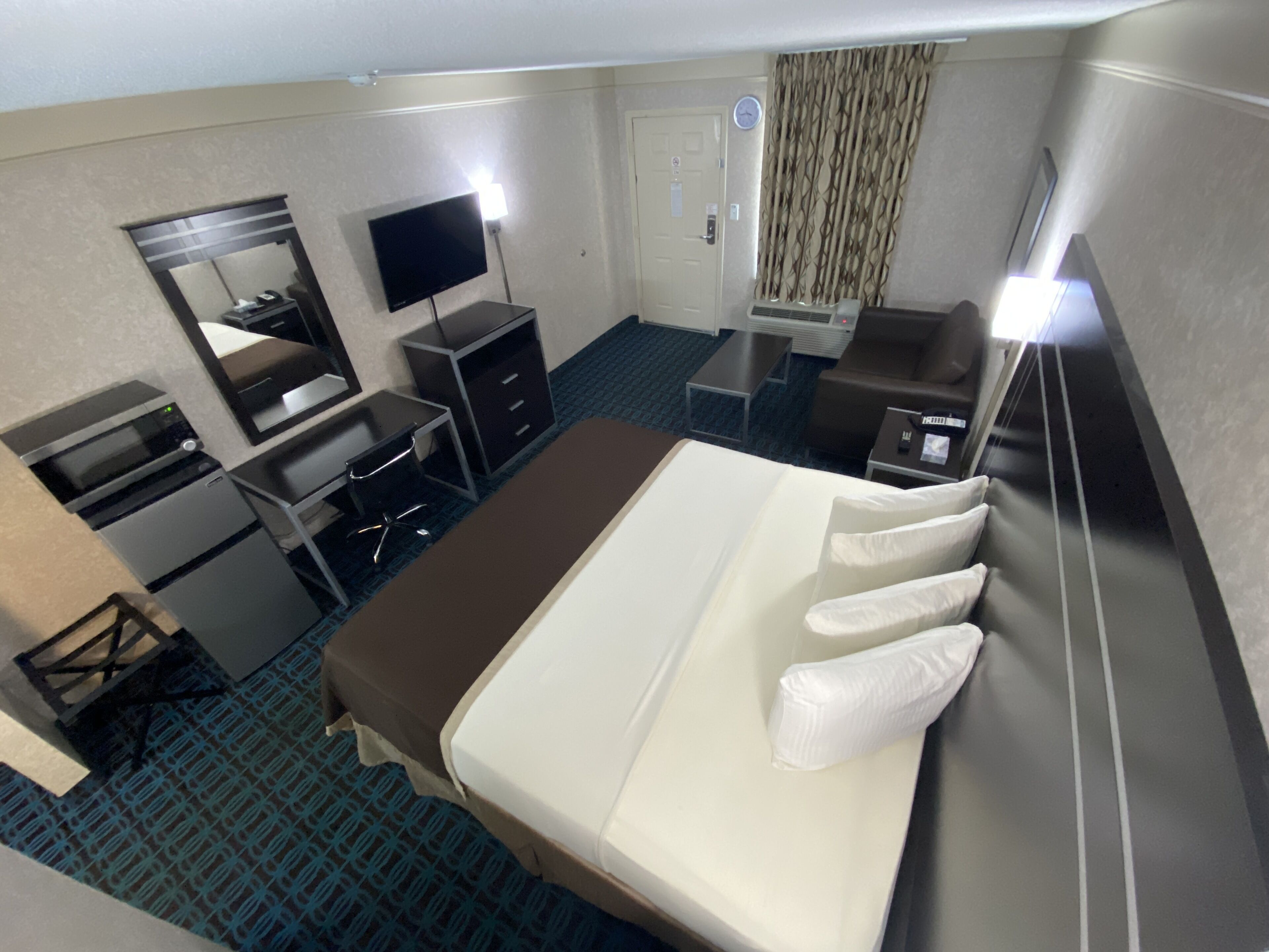 Una habitación de hotel con cama, escritorio, silla, televisor y baño.