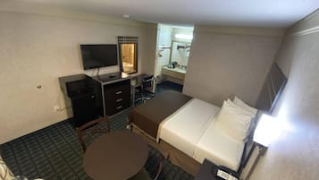 Une chambre d’hôtel comprenant un lit, un bureau avec une télévision, une chaise, une petite table et un téléphone.