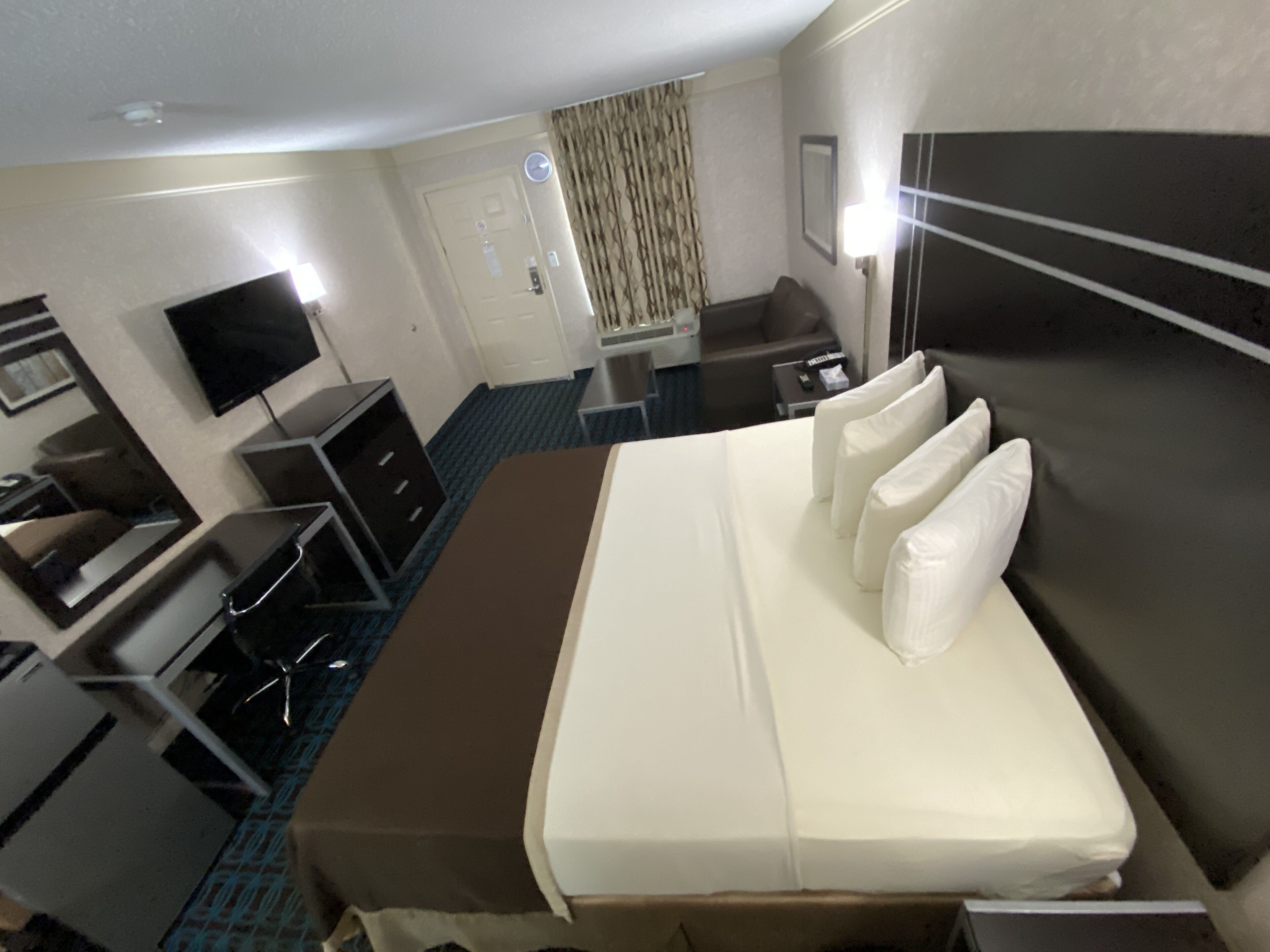 Una habitación de hotel con cama, escritorio, silla, televisor y baño.