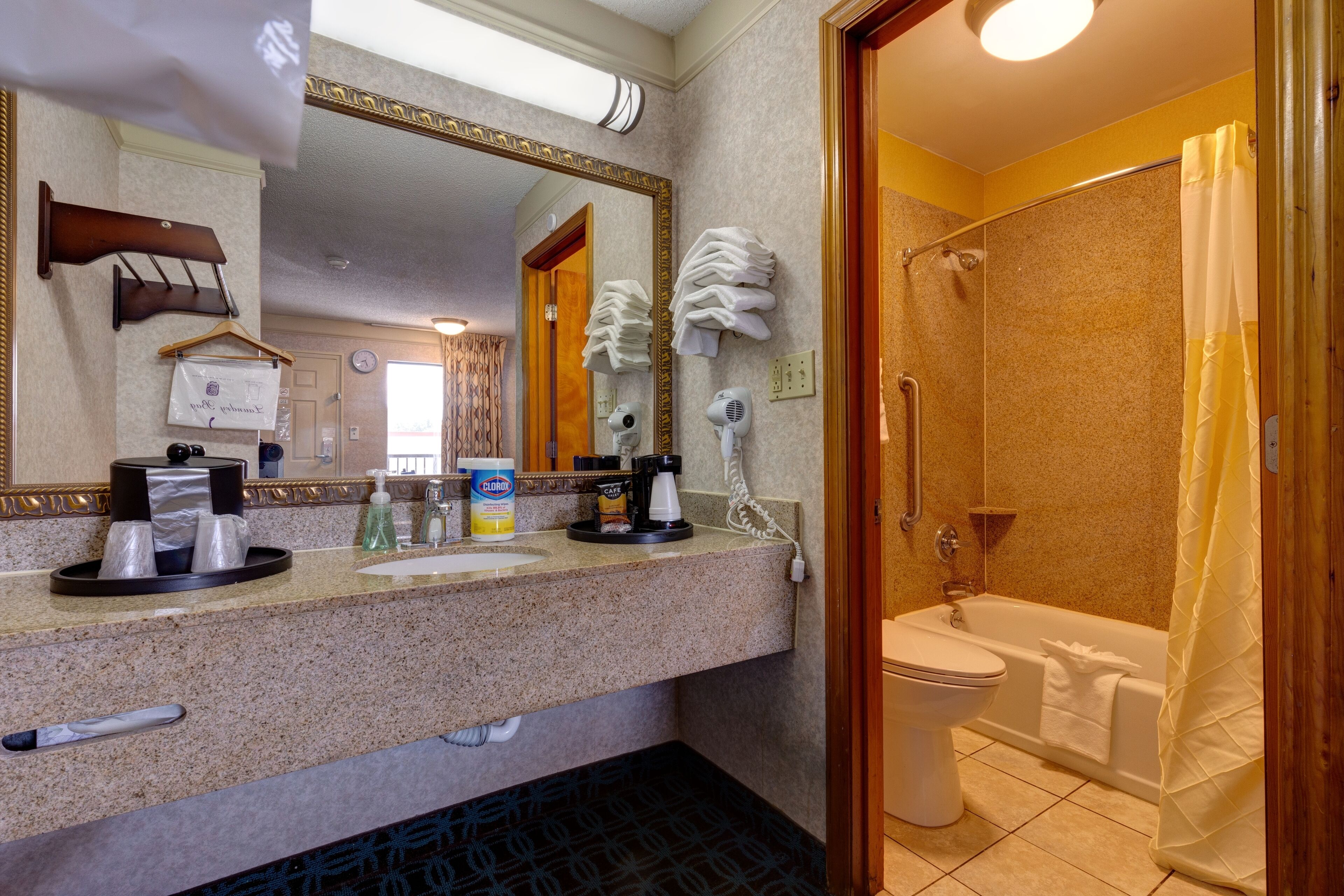 Un baño de hotel con lavamanos, espejo, toallero y zona de ducha.