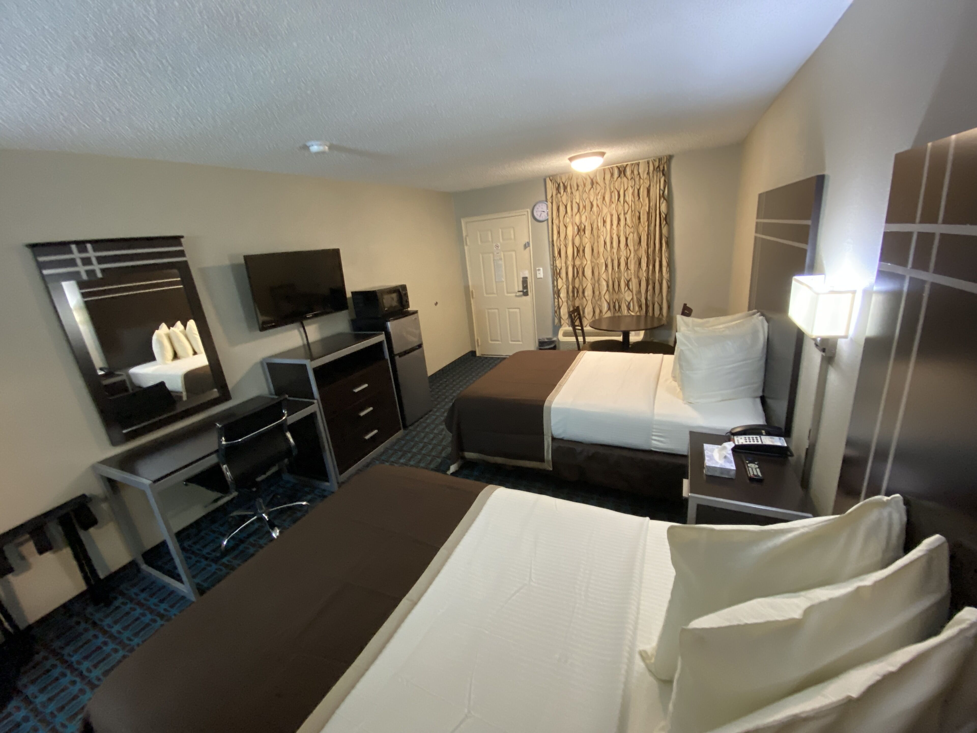 Habitación de hotel con cama, escritorio con computadora, televisión y una mesita.