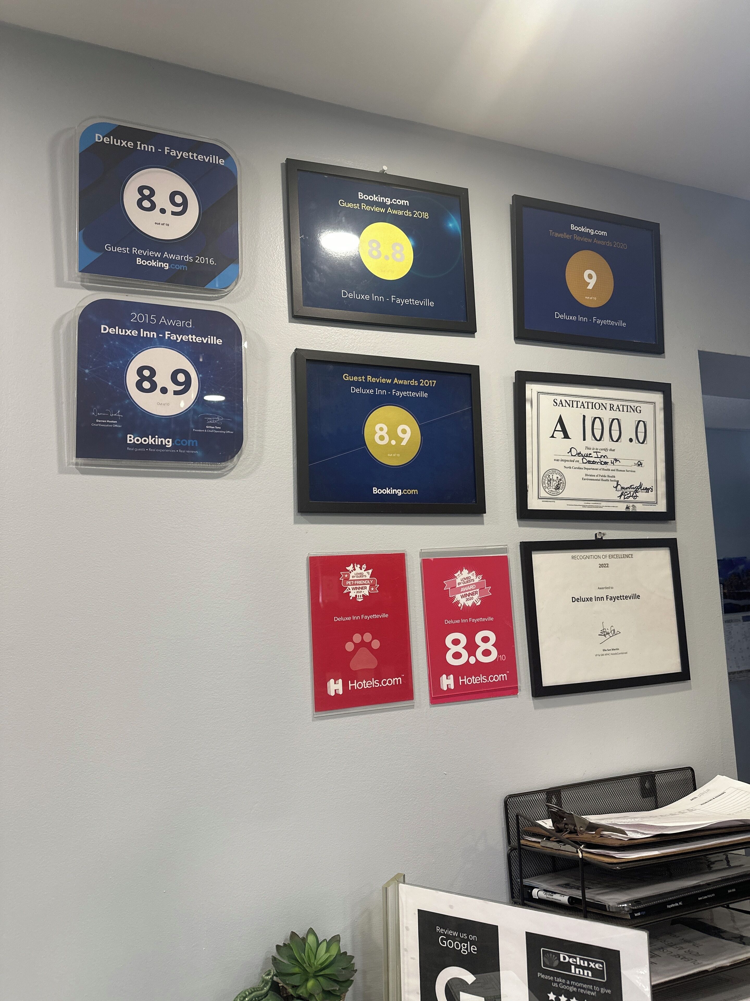 A wall displaying various awards and recognitions for a hotel, including multiple 8.9 ratings from different years and a 2022 Recognition of Excellence award.