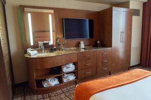 Un baño de hotel con un espejo grande, un televisor de pantalla plana, un lavamanos y un armario.
