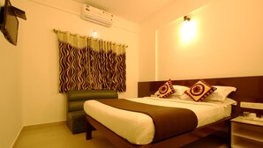 A neatly arranged hotel room with a bed, bedside table, and a small seating area. - Hotel Udupi Park Inn (Bengaluru)