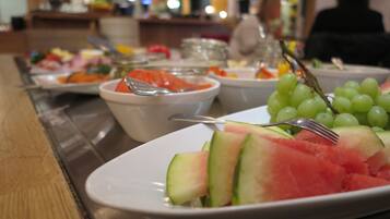 Una mesa de buffet con diversos platos, incluyendo sandía y uvas.
