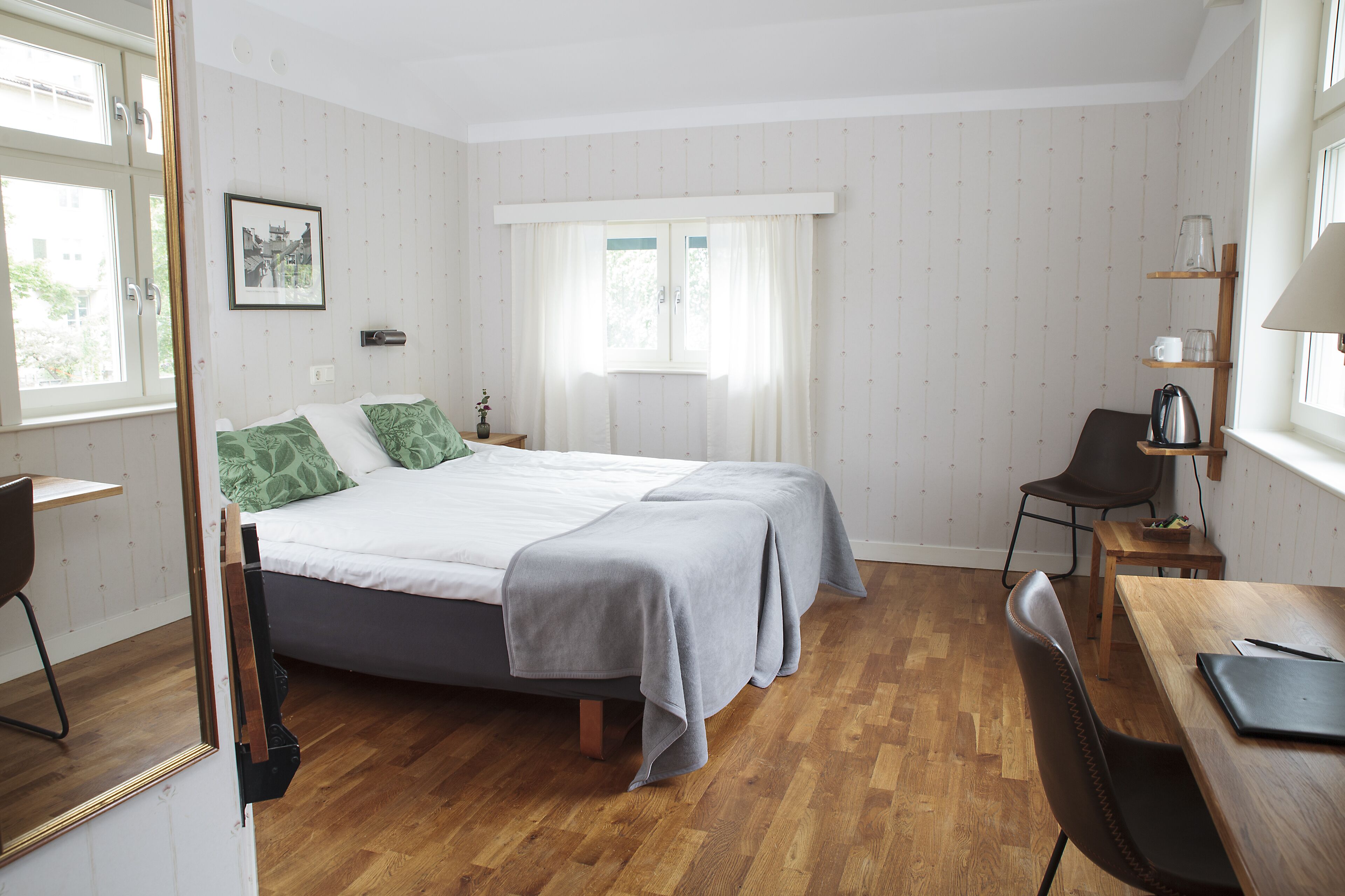 A bedroom with a bed, a desk, a chair, and a window with curtains.