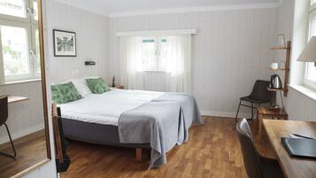 A bedroom with a bed, a desk, a chair, and a window with curtains.