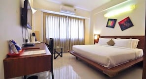 Una habitación de hotel con cama, escritorio, silla y obras de arte en la pared.