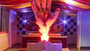 A room with a central hand-shaped light fixture, checkered walls, and a bar area. - Hotel Ekaa (Bengaluru)