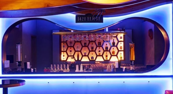 Zona de bar con una lámpara de forma hexagonal y un letrero que dice "1428 ELMST".