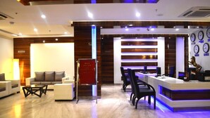 A modern hotel lobby with a reception desk, seating area, and a wall with clocks. - Hotel Ekaa (Bengaluru)