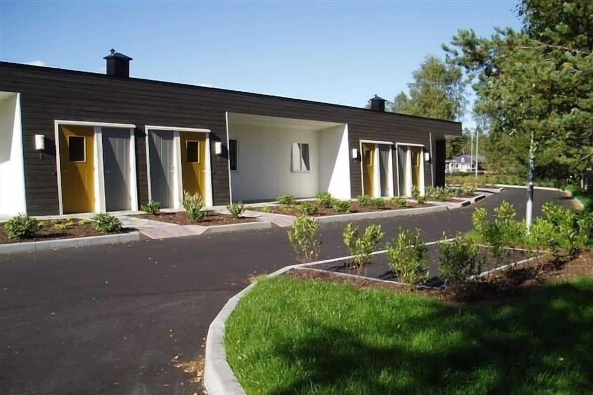 A modern building with multiple entry doors, a paved driveway, and a well-maintained lawn.