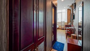 A hallway with dark wooden doors, a dining area with a table and chairs, and a large window with curtains. - Xavier Hotel (Ho Chi Minh City)