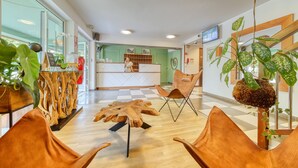 A reception area with a wooden reception desk, a large mirror, and a plant. - Residence Tropic Appart'hotel (Saint-Paul)