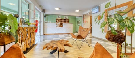 A reception area with a wooden reception desk, a large mirror, and a plant.