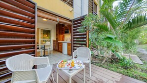A deck with white chairs and a table set with breakfast. - Residence Tropic Appart'hotel (Saint-Paul)