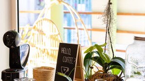 A coffee station with a sign reading "Hello, Coffee?" and a potted orchid. - Residence Tropic Appart'hotel (Saint-Paul)