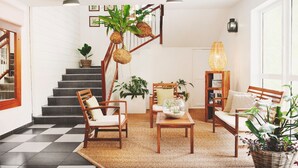 A modern living room with a checkered floor, wooden furniture, a staircase, and various plants. - Residence Tropic Appart'hotel (Saint-Paul)