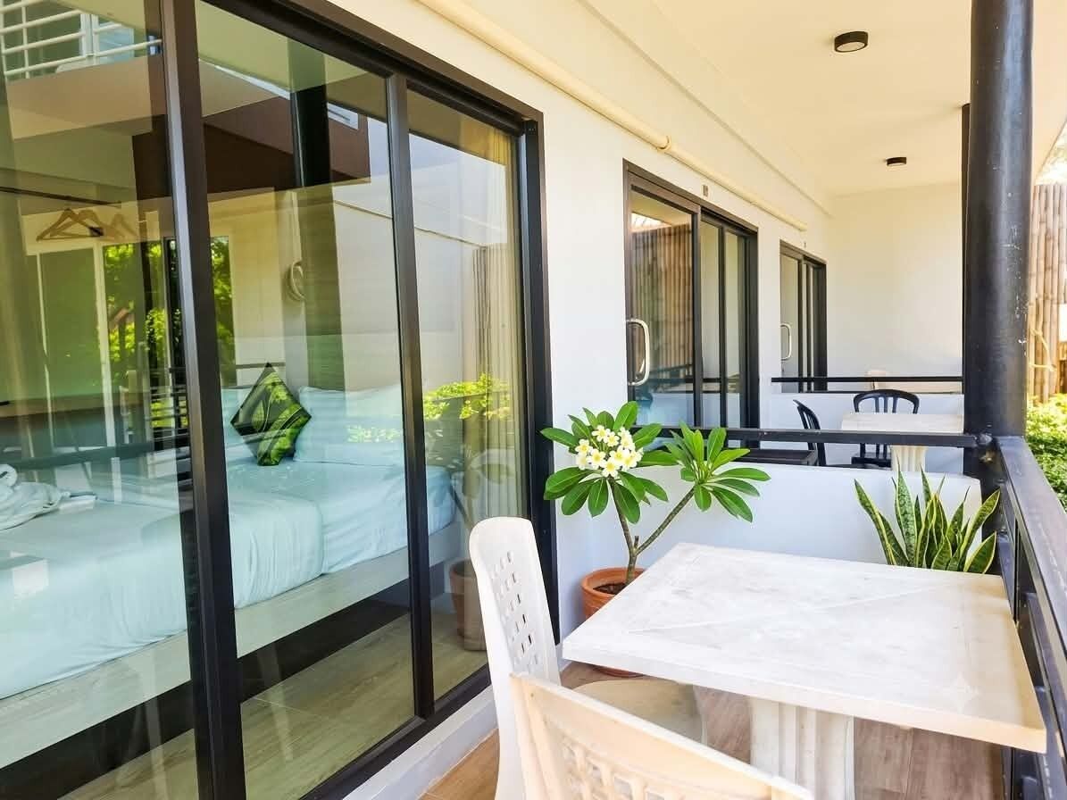 A balcony with a table, chairs, and potted plants.
