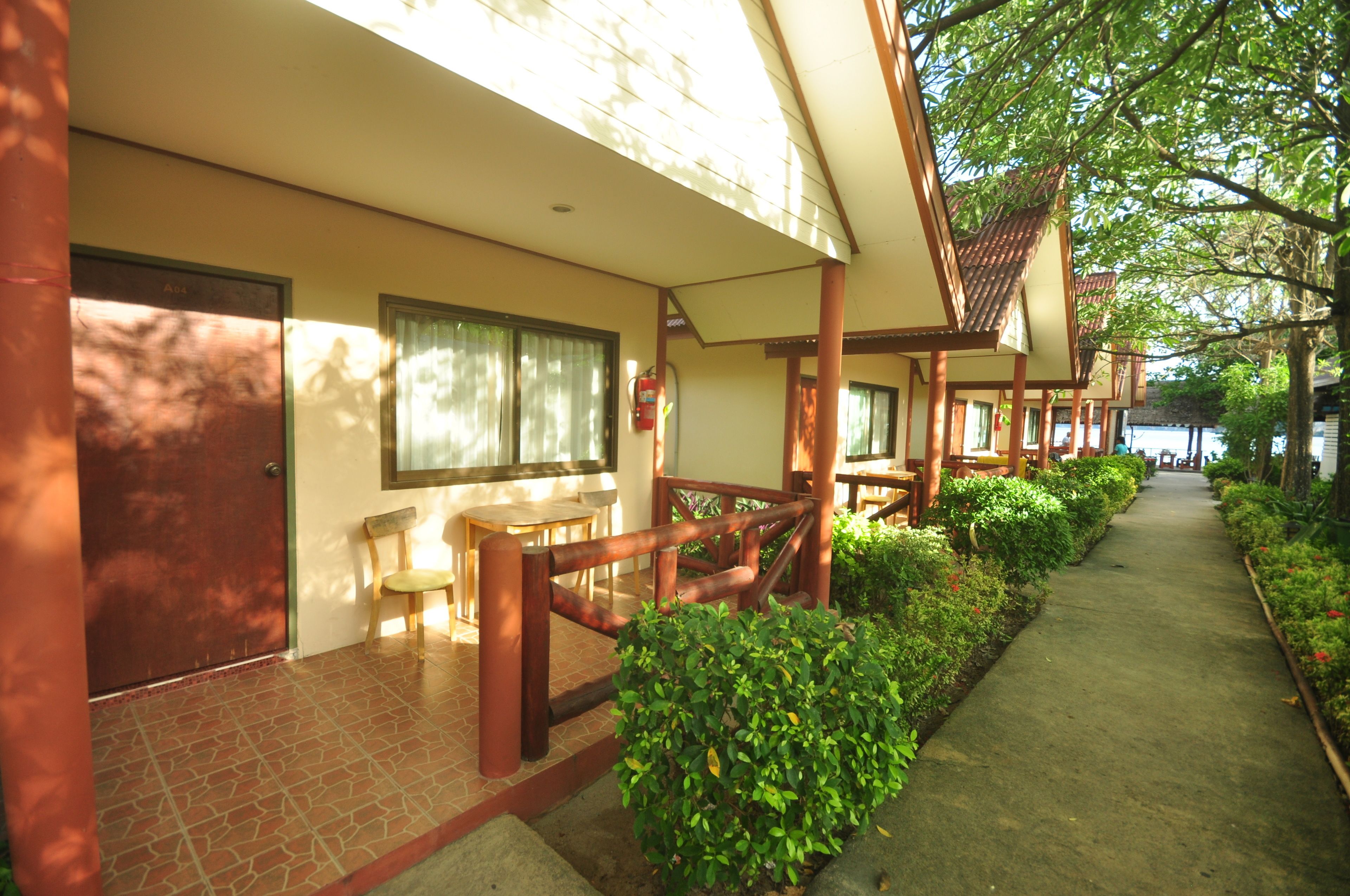 A corridor with wooden railings, a fire extinguisher, and a pathway lined with greenery.