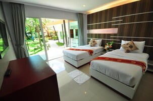 Habitación de hotel con dos camas, un escritorio y vistas a un jardín.