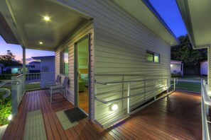 A covered outdoor area with a wooden deck, a metal railing, and a door leading to a building. - Chinchilla Motor Inn (Chinchilla)