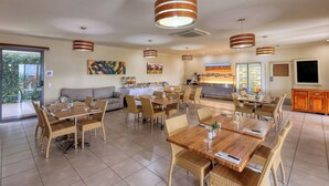 A spacious dining area with multiple tables and chairs, a sofa, and a kitchen area with a refrigerator and counter. - Chinchilla Motor Inn (Chinchilla)