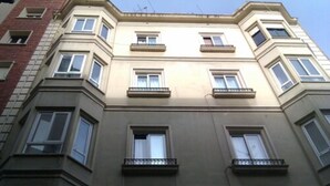 Um edifício de vários andares com entrada na esquina, várias janelas e sacadas.