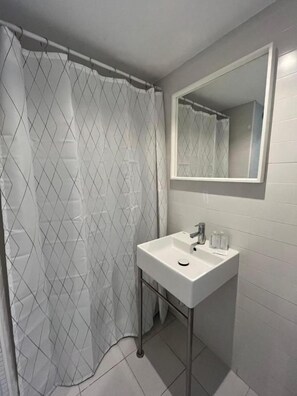 A bathroom with a shower curtain, a sink, and a mirror.