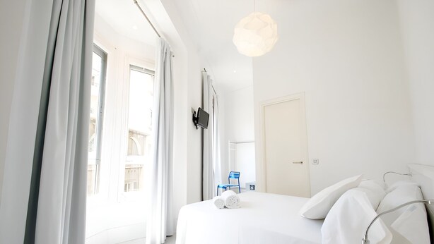 Quarto de hotel moderno com uma cama grande, televisão de tela plana na parede e vista para a varanda.
