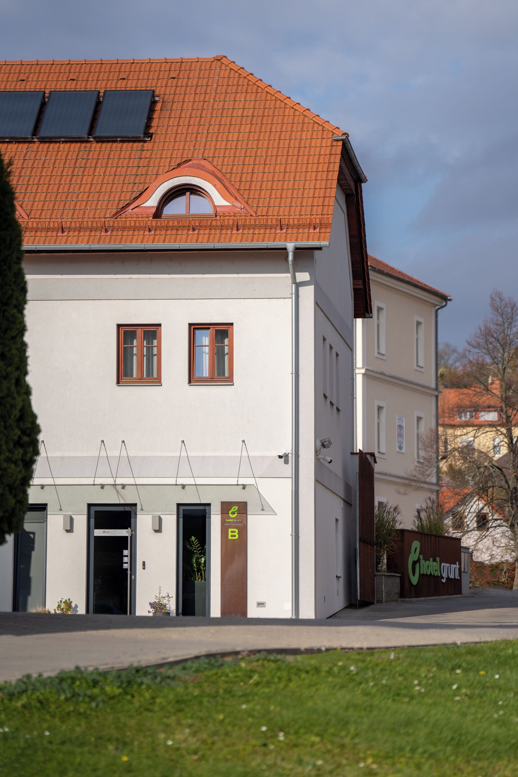 Ein Hotel mit rotem Ziegeldach, zwei sichtbaren Fenstern und einem Schild mit der Aufschrift 'Hotelgut'.