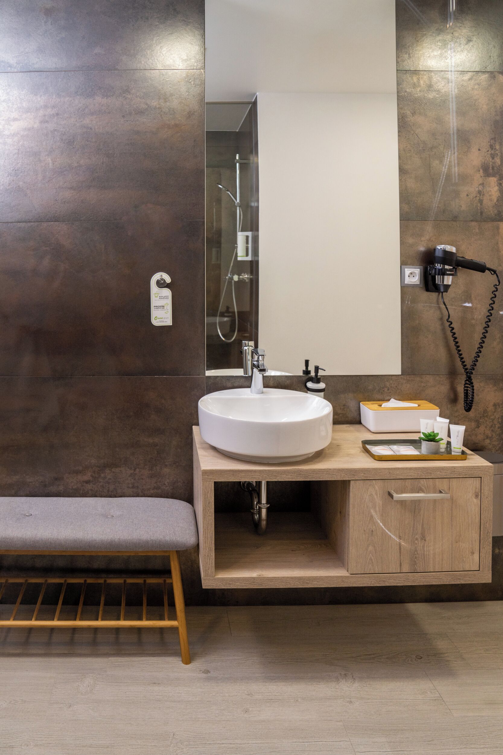 A modern bathroom with a large sink, mirror, and a bench.