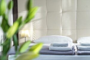 Una cama bien hecha con toallas dobladas y una lámpara de noche.