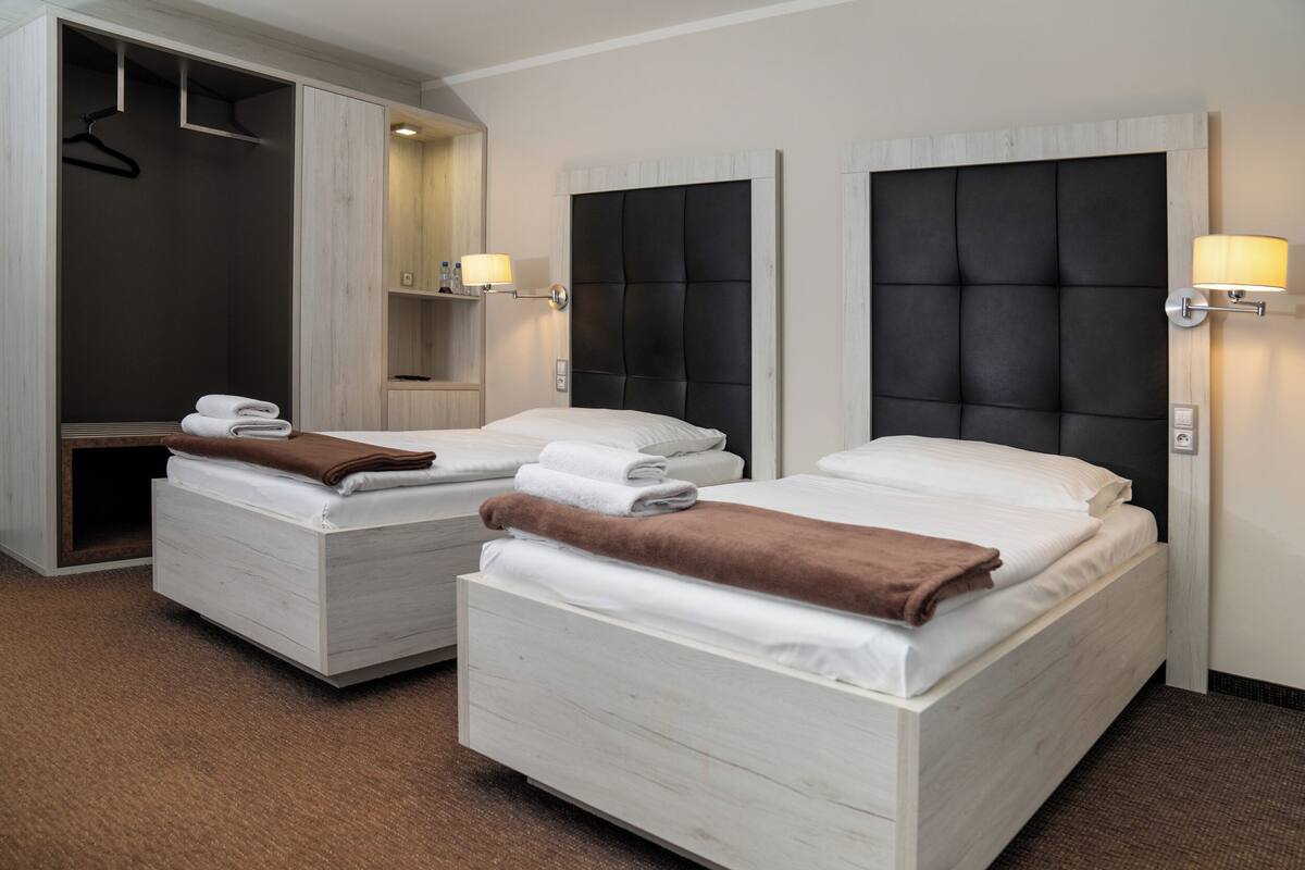 A hotel room with two beds, a walk-in closet, and bedside lamps.