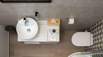 Un baño moderno con lavamanos, inodoro y ducha blancos.