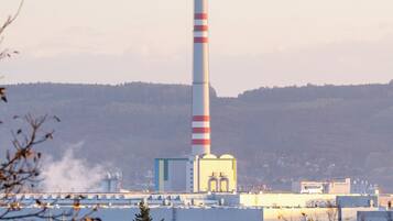Una alta chimenea con franjas rojas y blancas, rodeada de edificios industriales y casas residenciales.