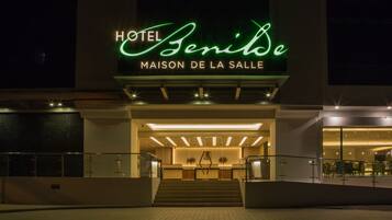 The exterior of Hotel Benilde with a modern facade, a prominent entrance, and a staircase leading to the lobby.