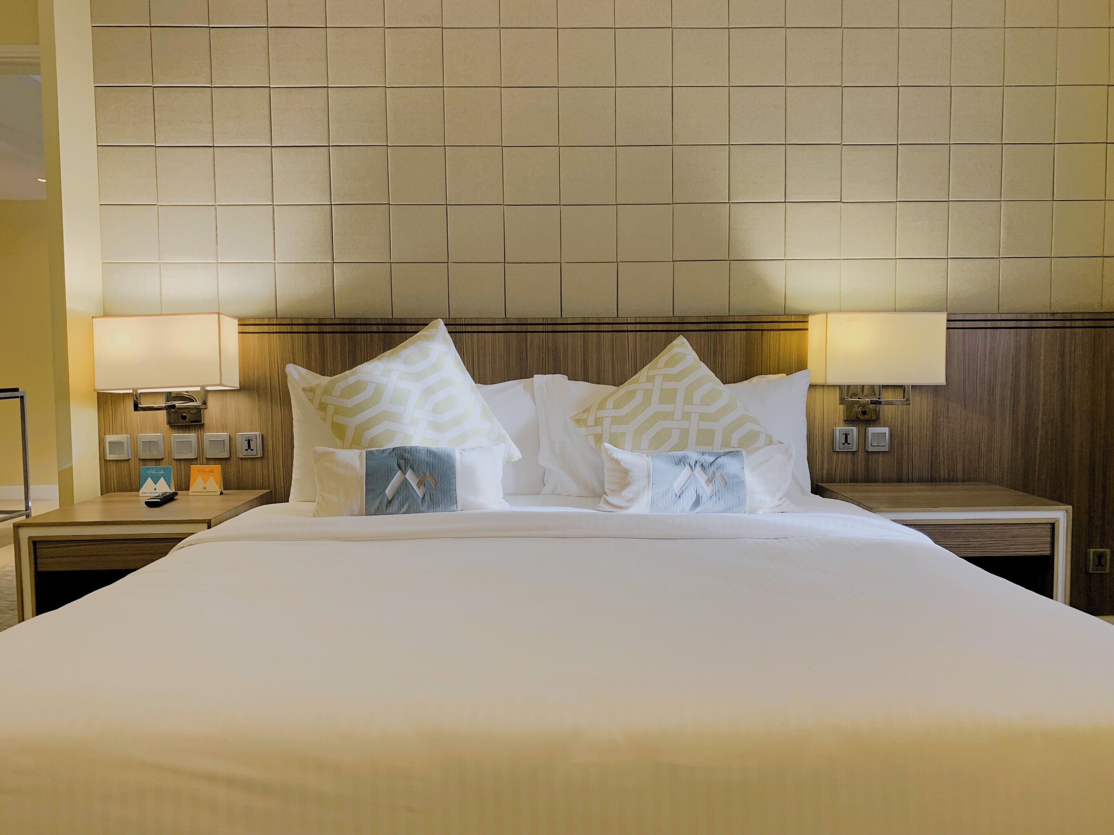 Een hotelkamer met een groot bed, twee nachtkastjes en een houten hoofdbord.