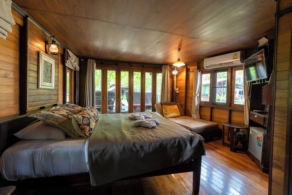 Una habitación de madera con una cama, un sofá, una mesita y un televisor.