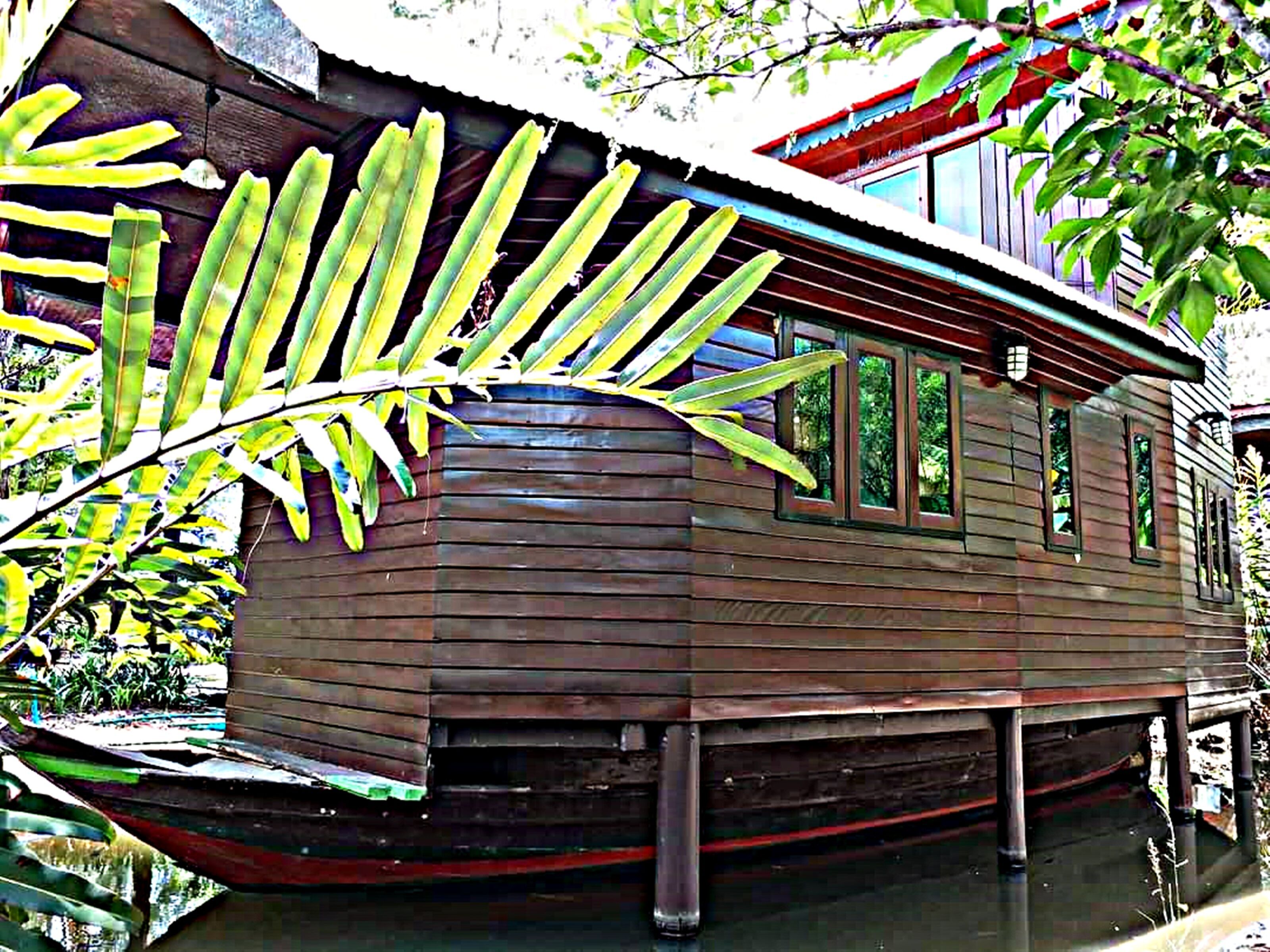 A wooden houseboat with a flat roof, windows, and a dock.