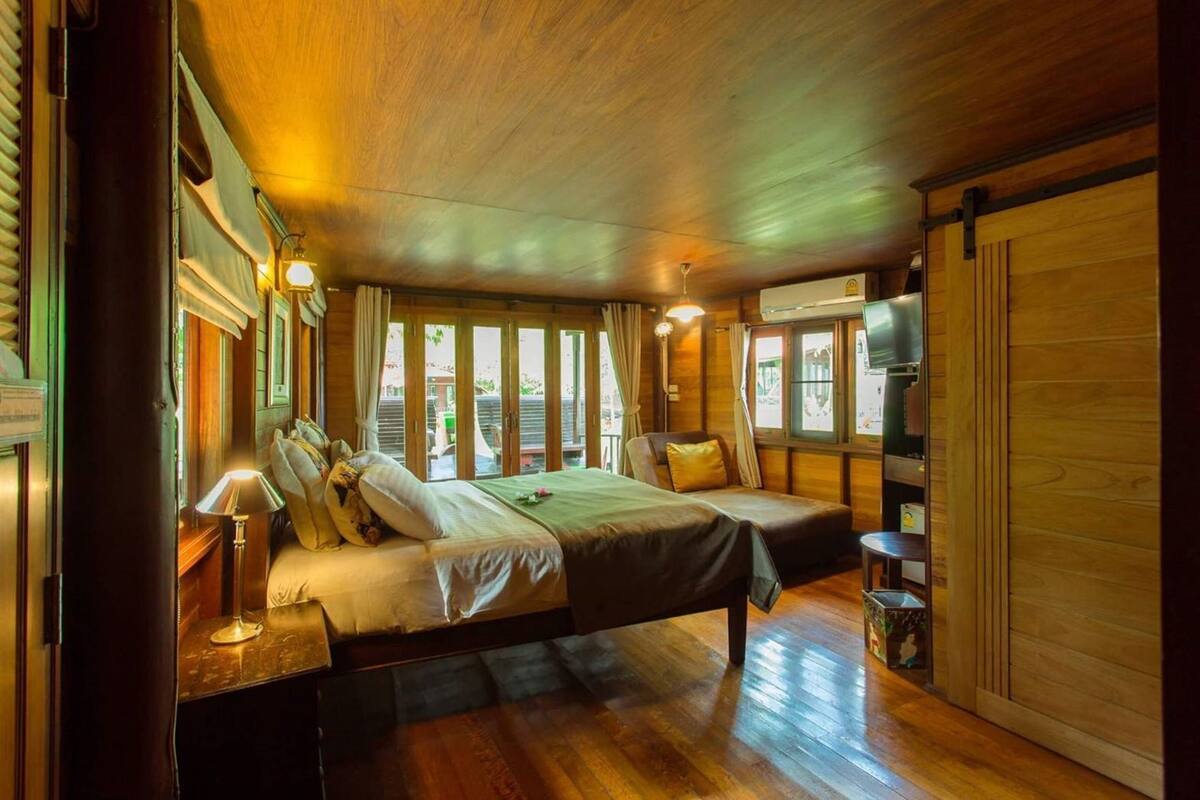 Una habitación con piso de madera, una cama, un televisor y una ventana.