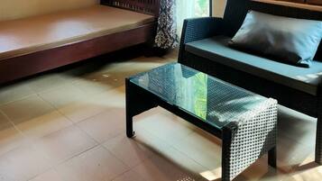 Una habitación acogedora con pared de ladrillo, un banco acolchado, un sofá y una mesa de centro de vidrio.
