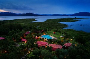 Vista aérea de un resort con piscina rodeada de exuberante vegetación y palmeras.