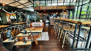 Un restaurante acogedor con interior de madera, una zona de bar y un espacio de comedor con mesas y sillas.