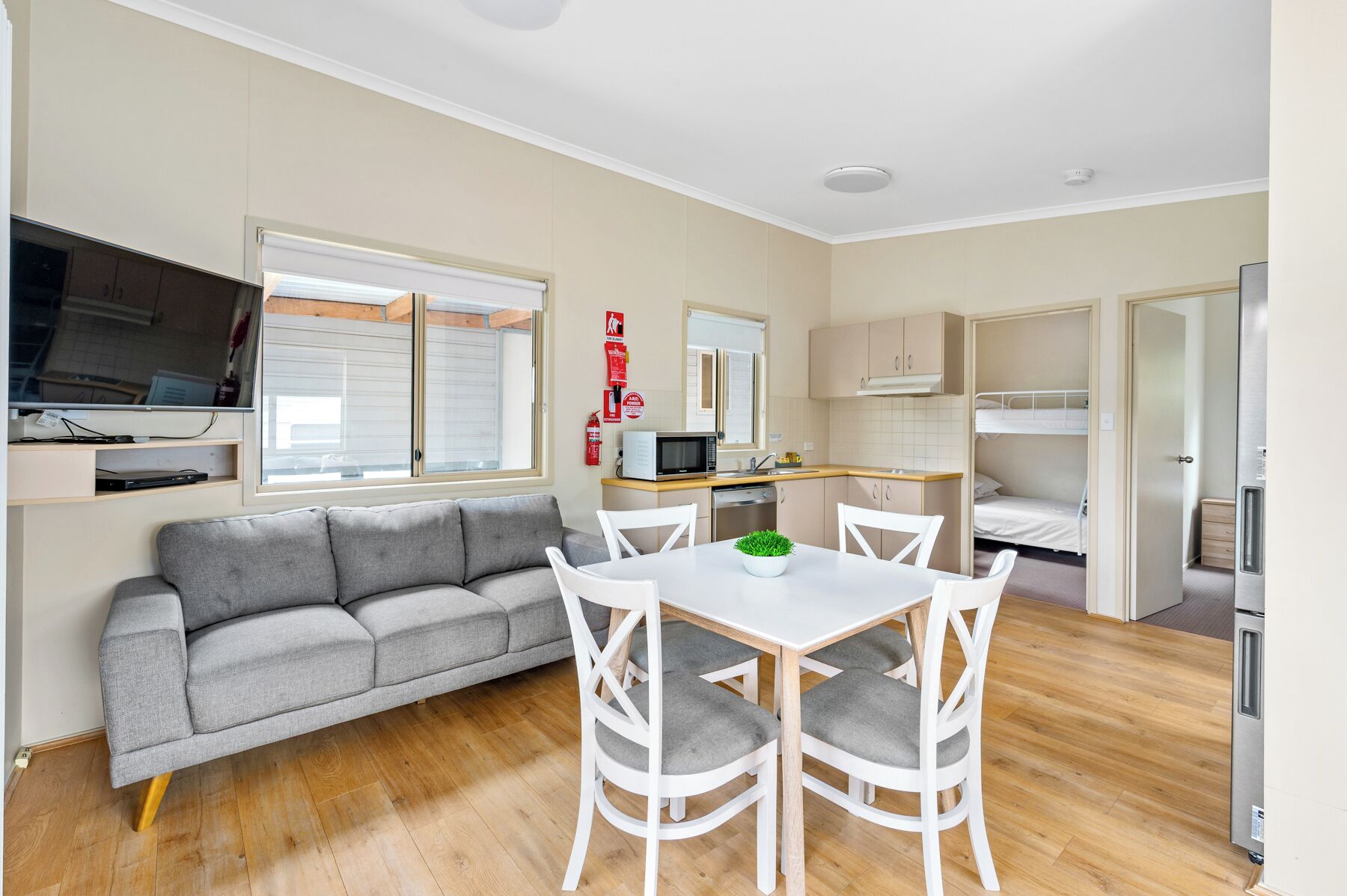 A compact living space with a sofa, dining table, chairs, a kitchenette, and a bed.