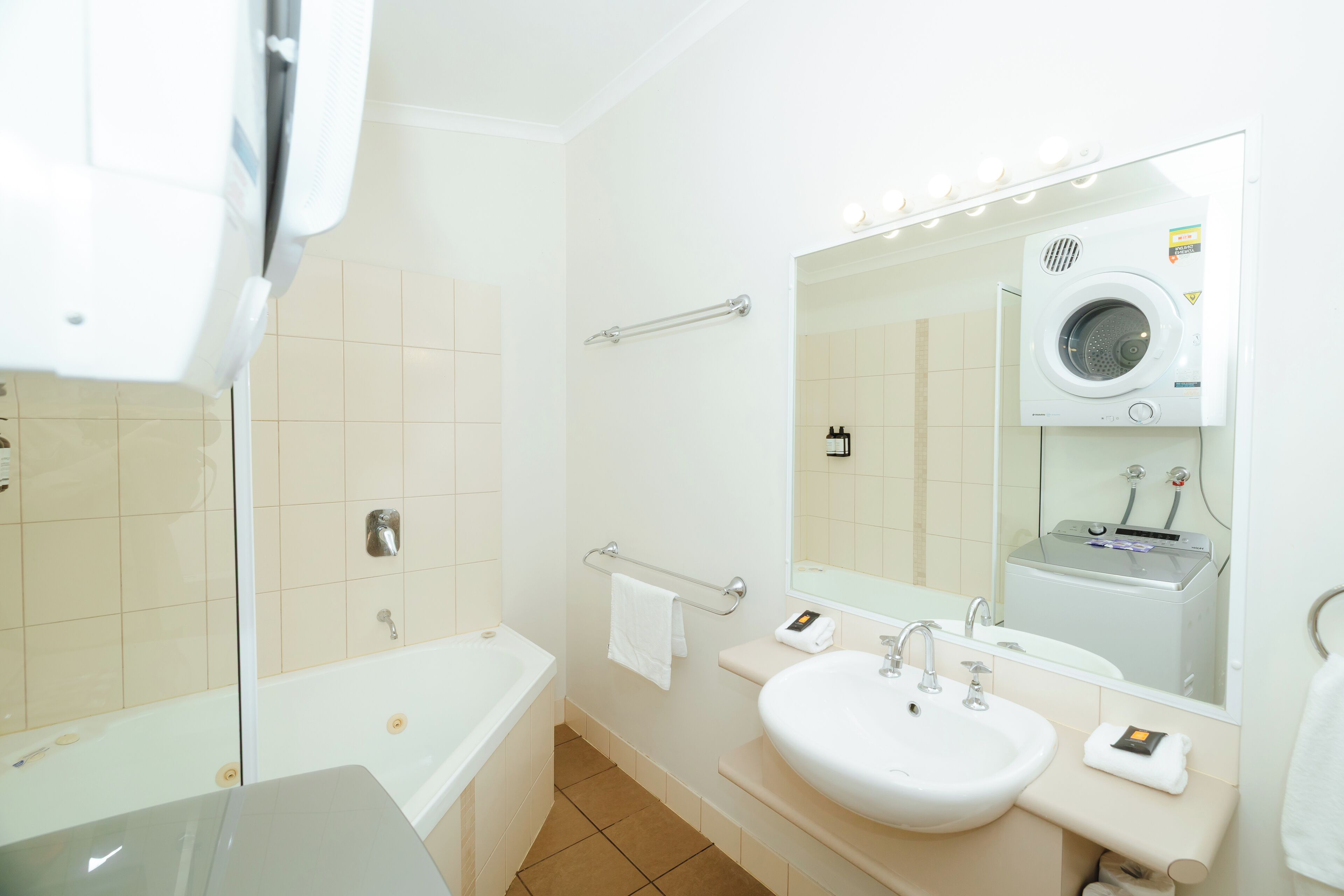 Un baño moderno con bañera, lavabo doble, espejo y lavadora integrada.