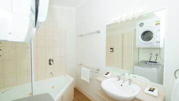 Un baño moderno con bañera, lavabo doble, espejo y lavadora integrada.